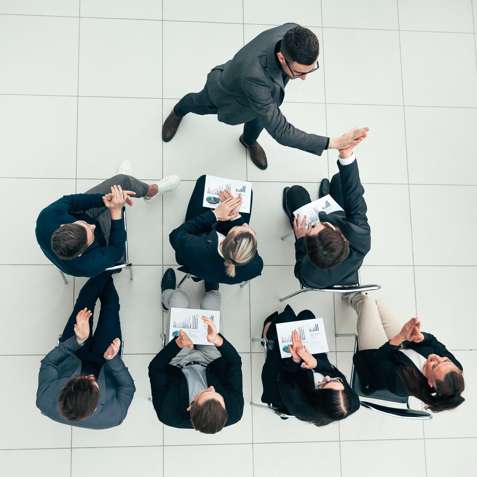 top view. happy employees giving each other a high five at a work meeting.